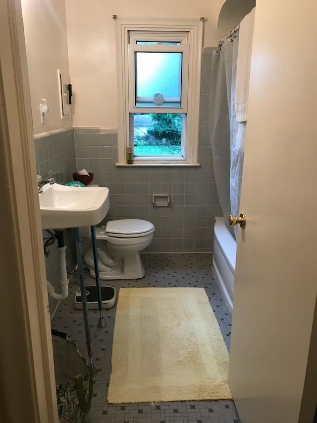 bathroom with tile patterned flooring, shower / bath combination with curtain, toilet, and tile walls