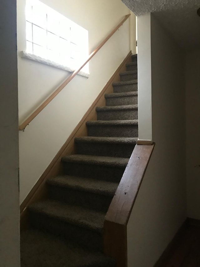 staircase featuring a textured ceiling