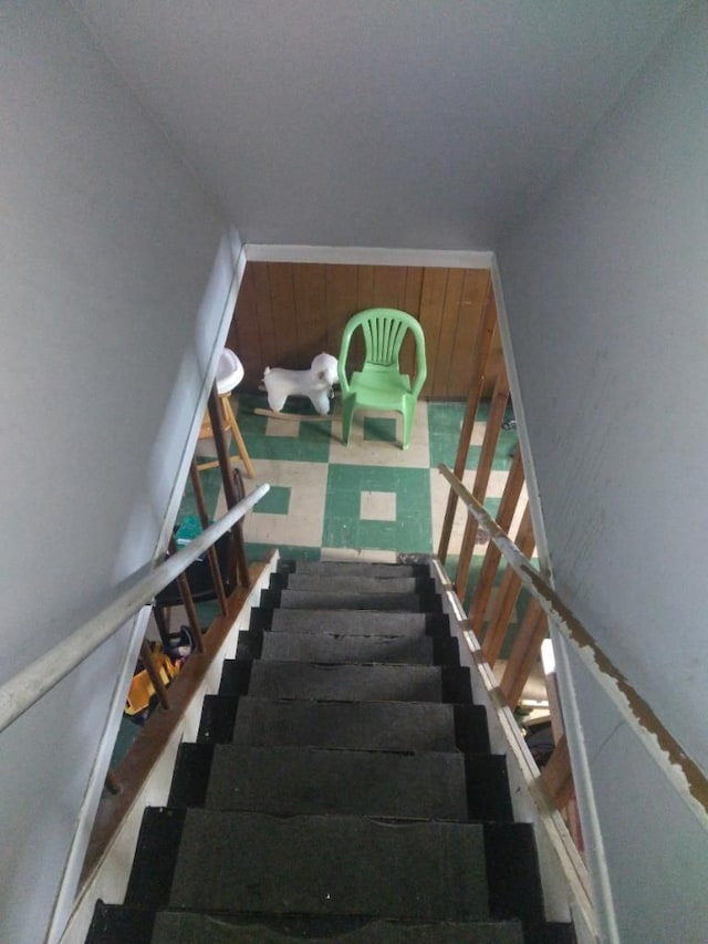 stairway featuring wooden walls