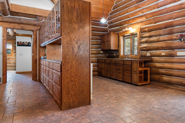 kitchen featuring rustic walls, sink, and pendant lighting