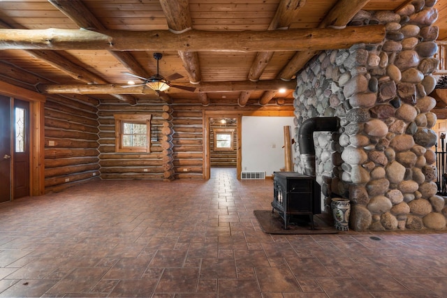 unfurnished living room featuring ceiling fan, a wood stove, rustic walls, and wooden ceiling