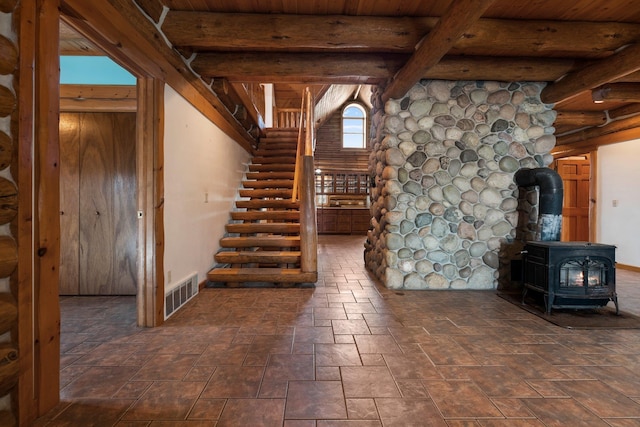 interior space with beamed ceiling, a wood stove, and wooden ceiling