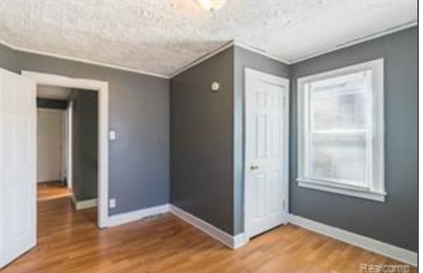 interior space featuring wood-type flooring, a textured ceiling, and ornamental molding