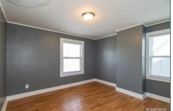 empty room with hardwood / wood-style flooring and ornamental molding