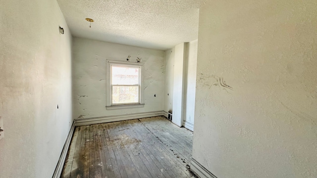 empty room with a baseboard radiator, wood-type flooring, and a textured ceiling