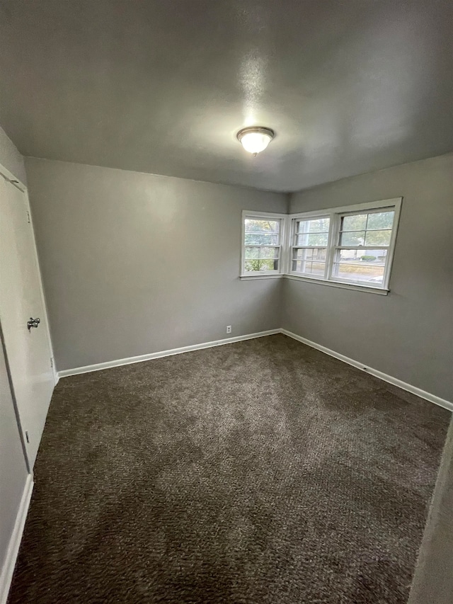 spare room featuring dark carpet