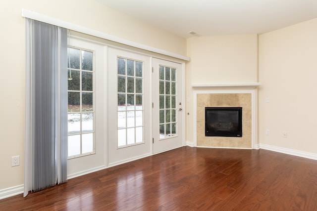 unfurnished living room with a tiled fireplace and dark hardwood / wood-style floors