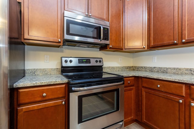 kitchen with light stone counters and appliances with stainless steel finishes