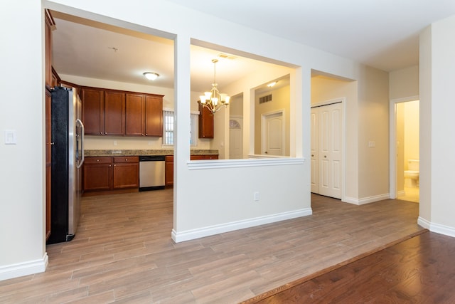 kitchen with light hardwood / wood-style flooring, decorative light fixtures, kitchen peninsula, stainless steel appliances, and a chandelier