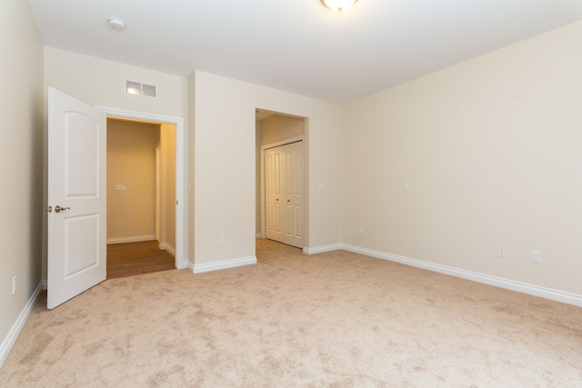 unfurnished bedroom with light colored carpet and a closet