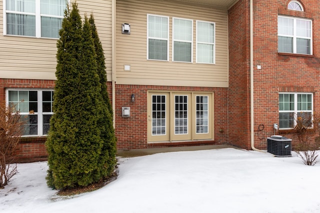 snow covered property with central air condition unit