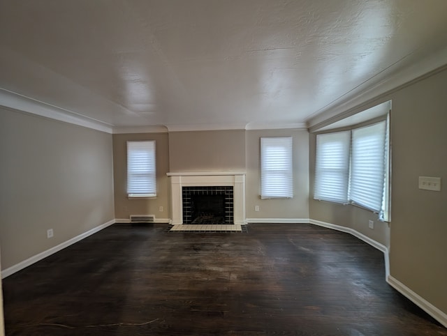 unfurnished living room featuring dark hardwood / wood-style floors, crown molding, and a tiled fireplace