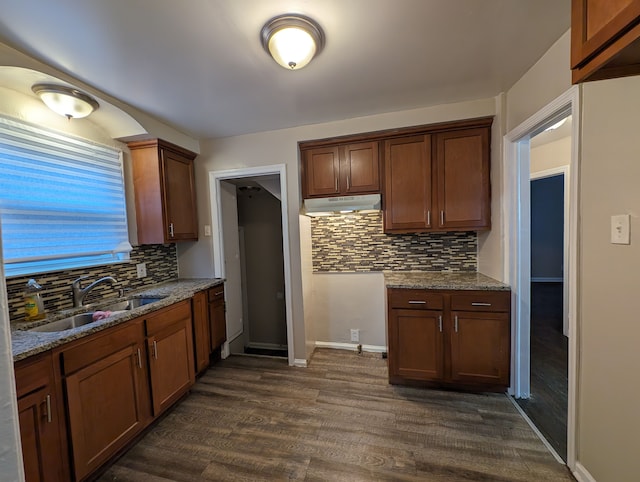 kitchen with tasteful backsplash, light stone countertops, sink, and dark wood-type flooring