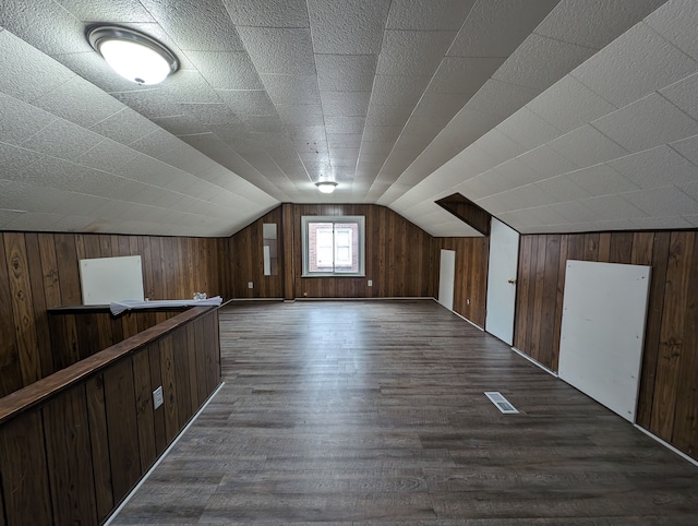 bonus room with wooden walls, dark hardwood / wood-style flooring, and vaulted ceiling