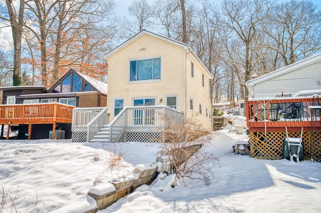 snow covered back of property with a wooden deck