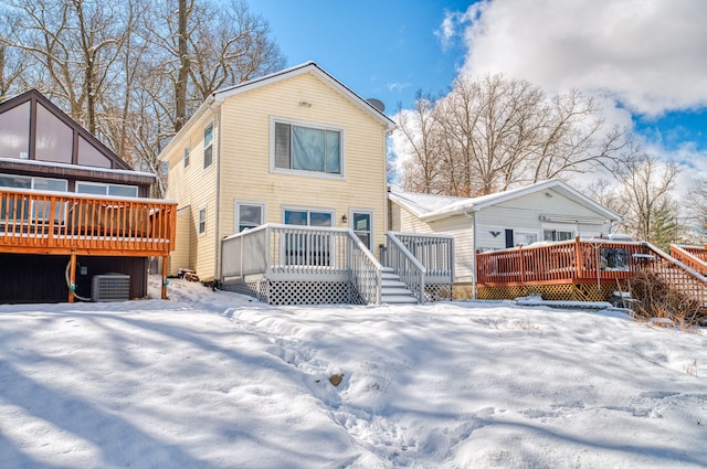 snow covered back of property featuring cooling unit and a wooden deck