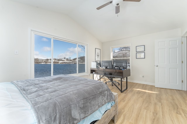 bedroom with lofted ceiling, a water view, light wood-type flooring, and multiple windows