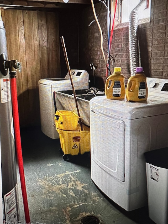 laundry room with washing machine and clothes dryer and brick wall