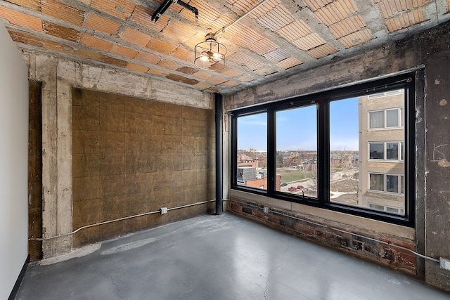 unfurnished room with a notable chandelier and concrete flooring