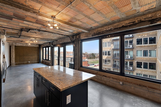 kitchen featuring pendant lighting, a notable chandelier, a kitchen island, and light stone counters