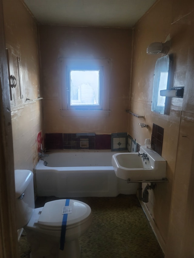 bathroom featuring a bathing tub, sink, tile walls, and toilet