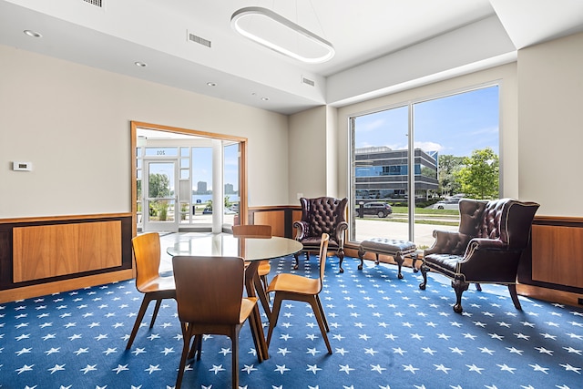 carpeted dining room with wood walls