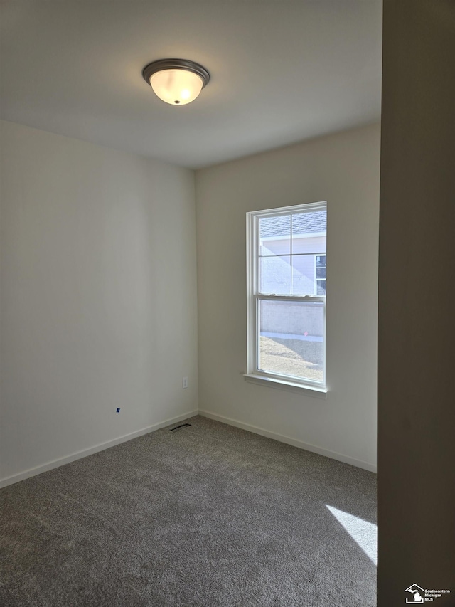 carpeted spare room featuring visible vents and baseboards