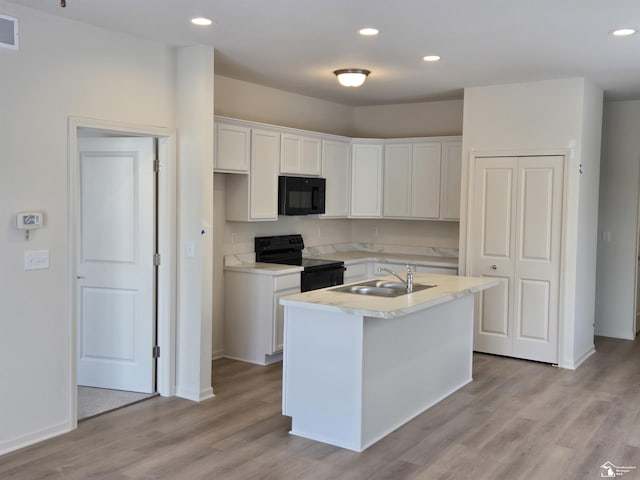 kitchen featuring a sink, white cabinetry, light countertops, black appliances, and an island with sink