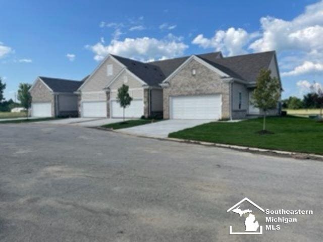 ranch-style home with an attached garage, concrete driveway, and a front yard