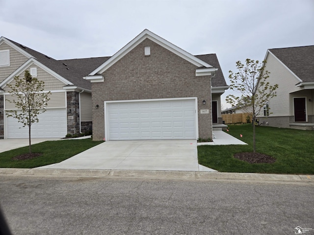 807 Plum Village Dr, Monroe, MI 48161 - view of front facade with a front yard, concrete driveway, stone siding, and roof with shingles