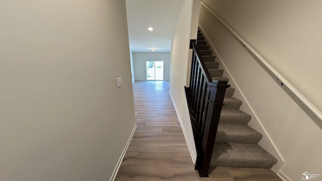 staircase featuring baseboards, wood finished floors, and recessed lighting