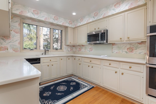 kitchen with cream cabinets, stainless steel appliances, light hardwood / wood-style floors, and sink