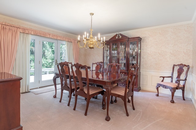 carpeted dining area featuring french doors, an inviting chandelier, and crown molding