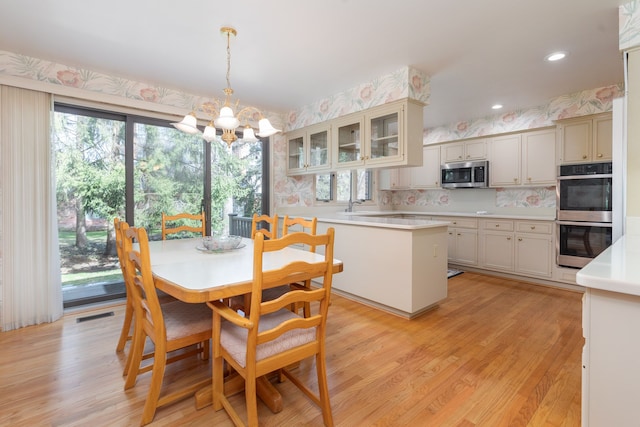 dining space with sink, a notable chandelier, and light wood-type flooring