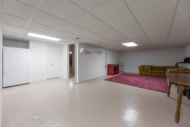 basement featuring a drop ceiling and white refrigerator