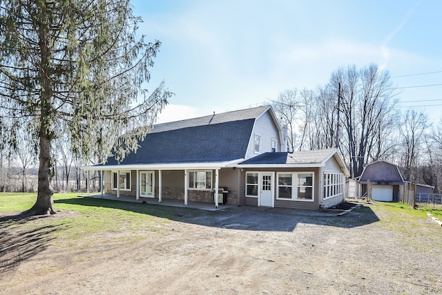 back of house with a porch, a garage, and an outbuilding