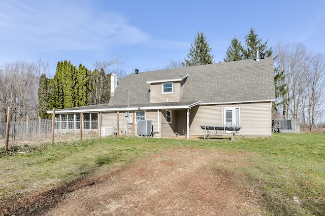 rear view of house with a yard, a sunroom, and central air condition unit