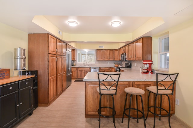 kitchen featuring kitchen peninsula, appliances with stainless steel finishes, tasteful backsplash, sink, and a breakfast bar area