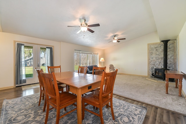 dining room featuring lofted ceiling, ceiling fan, dark hardwood / wood-style flooring, and a wood stove