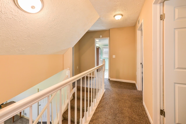 corridor with dark carpet and a textured ceiling