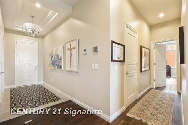 interior space with a raised ceiling, dark hardwood / wood-style flooring, and an inviting chandelier