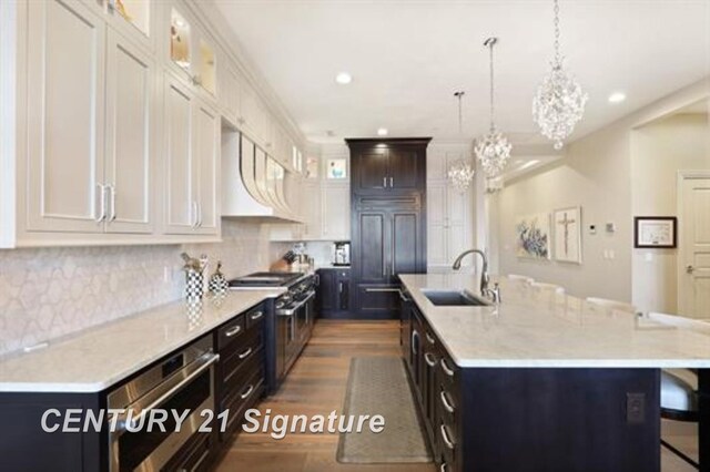 110 E Main St, Midland, MI 48640 - kitchen with a sink, a kitchen bar, recessed lighting, a kitchen island with sink, and dark wood-style floors