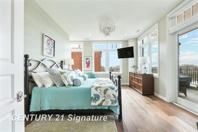 bedroom featuring a notable chandelier, wood-type flooring, access to outside, and multiple windows