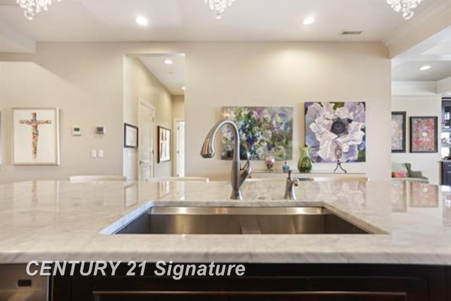 kitchen featuring light stone counters, sink, and an inviting chandelier