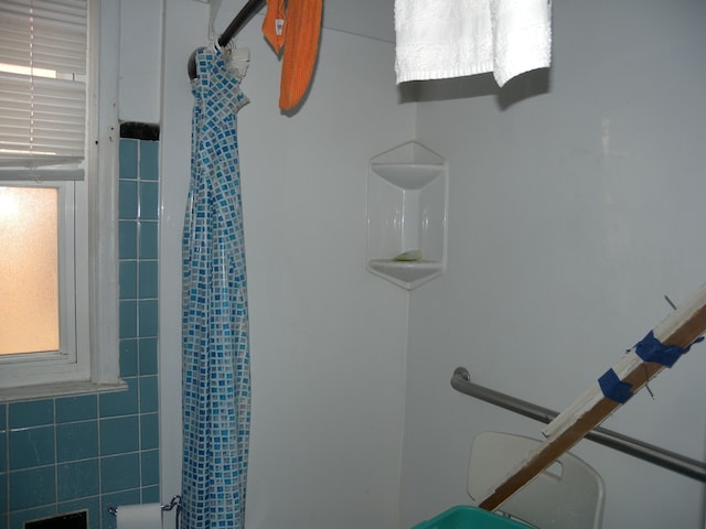 bathroom featuring a shower with curtain and tile walls