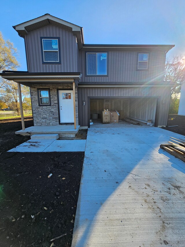 view of front facade featuring a porch, stone siding, board and batten siding, and concrete driveway