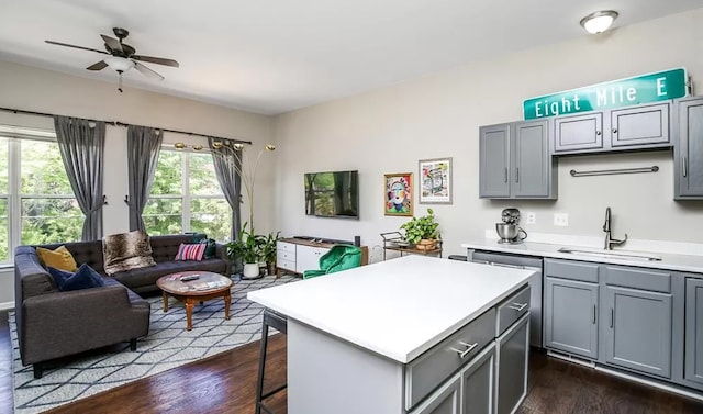 kitchen featuring ceiling fan, gray cabinetry, light countertops, a sink, and open floor plan