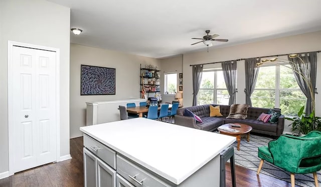 kitchen featuring gray cabinetry, a center island, light countertops, ceiling fan, and dark wood-style flooring