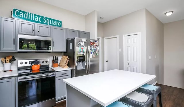 kitchen with a center island, a kitchen bar, light countertops, gray cabinets, and stainless steel appliances