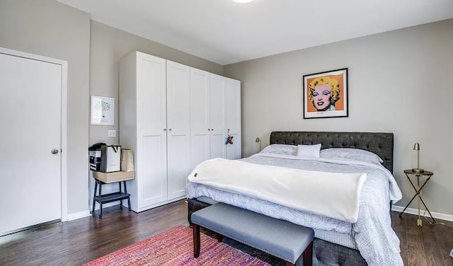 bedroom with dark wood-type flooring, baseboards, and a closet